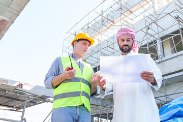 Fototapeta na wymiar Arabic businessman teammates working together, construction engineer architect and worker looking building model and blueprint blueprint plans of Arab businessman.