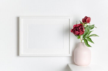 Landscape blank frame mockup on white wall with fresh flowers