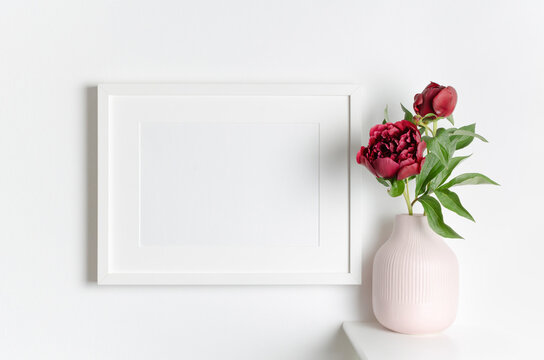Landscape blank frame mockup on white wall with fresh flowers