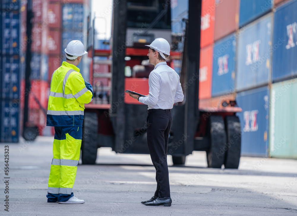 Poster Manager and professional container yard workers checking stock for loading in the container yard warehouse,Logistic shipping yard business.