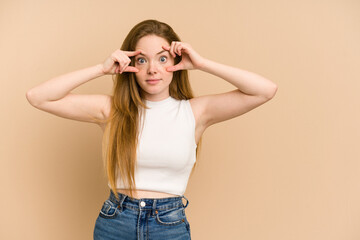 Young redhead woman cut out isolated keeping eyes opened to find a success opportunity.