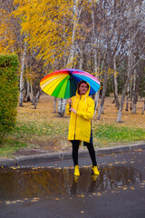 a girl under an umbrella in the rain walks in the park
