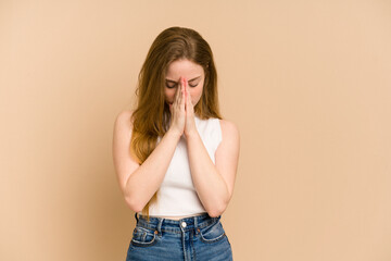 Young redhead woman cut out isolated praying, showing devotion, religious person looking for divine...