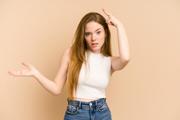 Young redhead woman cut out isolated holding and showing a product on hand.