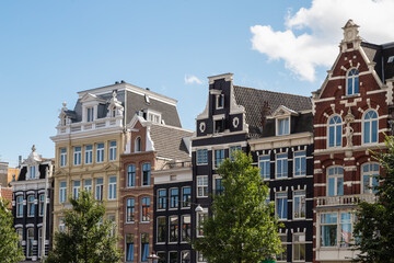 Historic facades of the canal houses along the river Amstel in Amsterdam. - obrazy, fototapety, plakaty