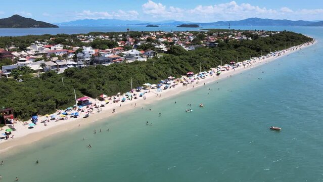 Aerial drone scene of quiet beach with lots of vegetation and people enjoying the sea and sand on the beach in Florian&oacute;polis Daniela beach