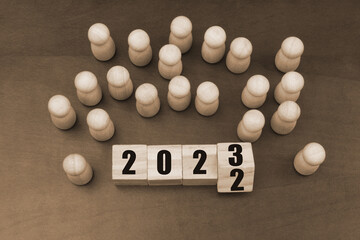 People figures and wooden cubes with flipping numbers 2022 and 2023.