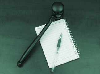 Notepad with pen and wooden judge gavel on table. 