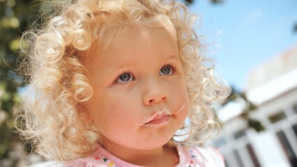 Fototapeta premium Portrait of a funny girl with leftover cream from a cake.