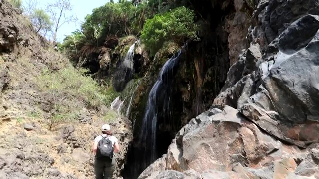Panning upward shot of tourists reaching their destination of the Engare Sero Waterfall