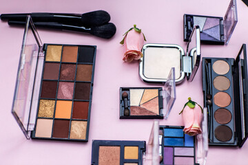 make up brushes with eyeshadows on pink background 