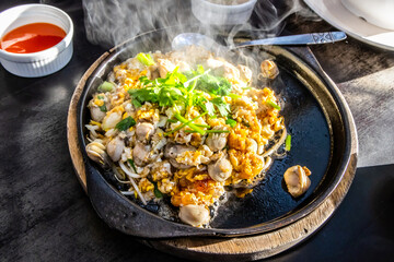 Hot pan of crispy fried oyster omelette served with bean sprout and spicy sauce.