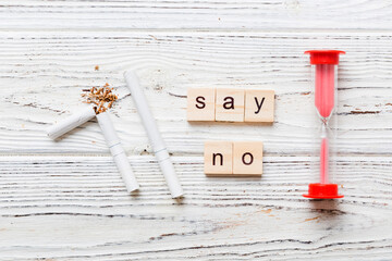 Cigarette And Wooden Blocks, Broken cigarette on table background with hourglass, No Tobacco Day with hourglass, clock health concept. time to quit smoking