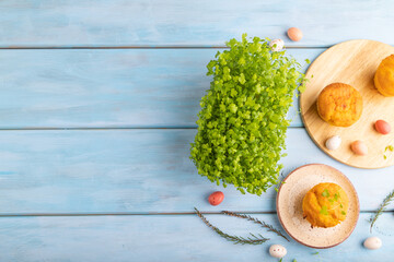 Homemade cakes with chocolate eggs and spinach microgreen on a blue, top view.
