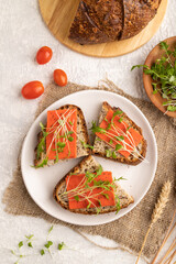 Grain bread sandwiches with red tomato cheese and microgreen on gray,  top view, close up.