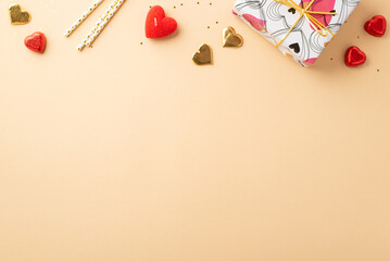 Valentine's Day concept. Top view photo of giftbox heart shaped candies straws candle and golden sequins on isolated pastel beige background with copyspace