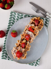 Belgian waffles with fruit and powdered sugar on a white background with a towel. Breakfast.