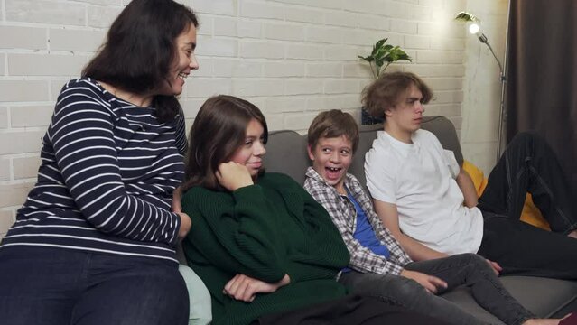 mother and three children, sitting on the sofa, watching TV