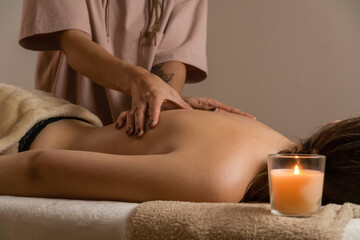 Obraz na płótnie Canvas Female masseur does a relaxing back massage in a spa salon with lit candles. Concept of health, body care