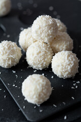 White coconut pralines on a black granite background. Selective focus, shallow depth of field