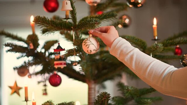 Weibliche Hand h&auml;ngt Kugel in Weihnachtsbaum.
