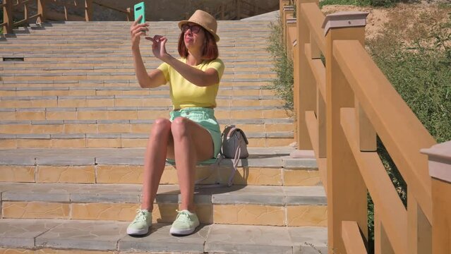Woman sitting on a stairs and making selfie in Aktau Kazakhstan. 4k footage UHD 3840x2160 
