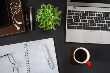 Top view of workplace with laptop and other items on black desktop