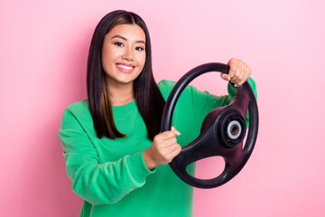 Photo of young positive experienced taxi driver chinese girl hold steering wheel new car owner automobile license isolated on pink color background