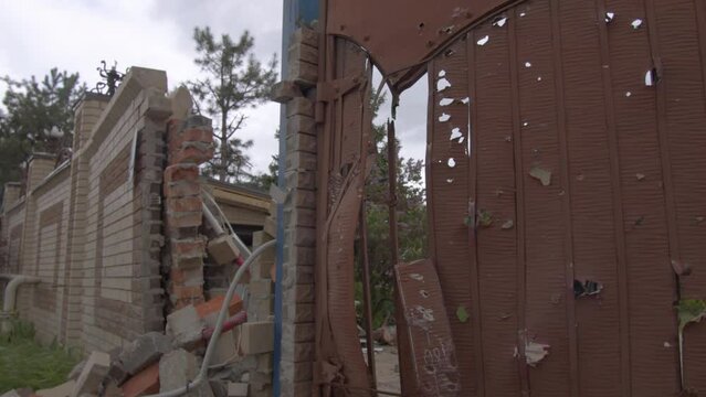Fence of residential house, destroyed by tank hit and Russian troops bullets in Eastern Ukraine during war. Bullet hole on gates of civilian property. Strike on residential area. Kharkiv 25.05.2022
