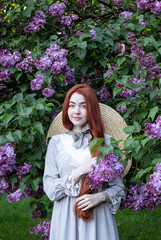 young girl with long red hair with lilac flowers  in the garden in spring