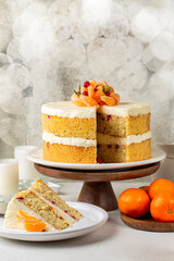 Festive fluffy almond flour sponge cake with cream made of tangerine and orange juice, white chocolate and cream cheese. Decorated with fresh mandarin fryits, cranberries. Homemade. Vertical.