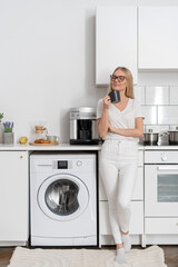 woman standing with mug and drink coffee at home kitchen