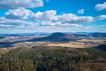 Clouds in blue sky with shadows on ground. A birds eye view of beautiful mountains covered with evergreen forest on sunny autumn day. Natural landscape with mountain ranges and valleys