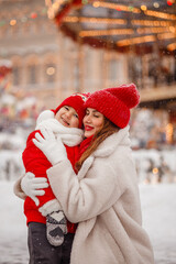 mother and son have fun at the Christmas market on the background of the carousel