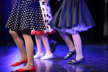 A woman in a group dancing on stage legs in red shoes polka dot dress close up