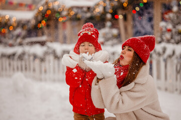 mother and son in warm clothes have fun in winter at a snowy New Year's fair on Red Square in Moscow