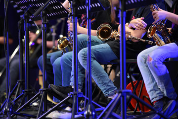 Musicians playing in a jazz orchestra on a saxophone sit in a row with a musical instrument.The...