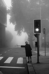 A woman in coat votes in the street in a thick fog. Black and white photo.