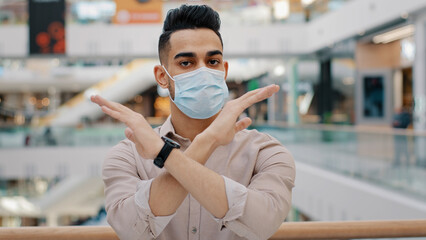 Indian Hispanic man in medical face mask show forbidden gesture stop crossed hands no not sign...