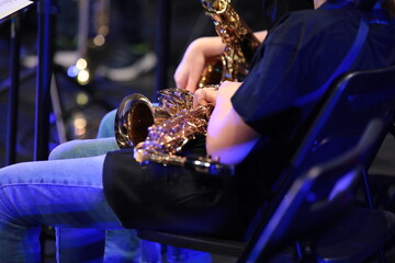 A saxophonist with a golden musical instrument sitting relaxed during a break from a school jazz...