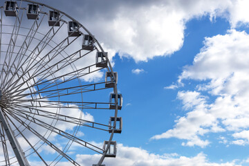 Big Ferris wheel and light blue sky with white clouds