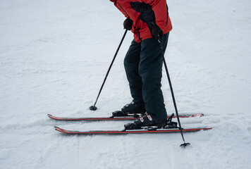 A man on alpine skis dressed in red ski jacket skiing down the ski slope.  Winter. Extreme sport and travel content  