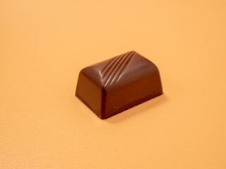 Chocolate candies on an orange background. Candies with filling.