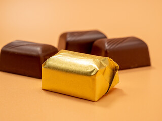 Chocolate candies on an orange background. Candies with filling.