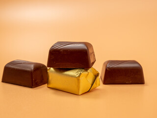 Chocolate candies on an orange background. Candies with filling.