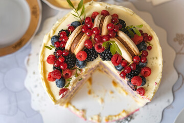 Top view on delicios cut cake decorated with fresh berries and macaroons cake. Dessert from confectioner. Close-up