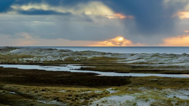 Amrum island, Germany: Time lapse of sun rays emerging through the dark storm clouds at the beach of Amrum. Sunset is obscured by a thick cloud front announcing bad weather