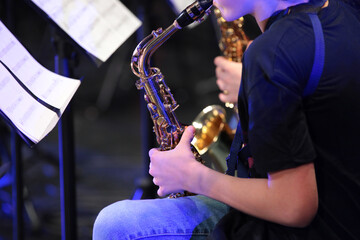 A person playing the saxophone by notes sitting in a jazz orchestra a close-up view of a musician...
