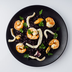 delicious black rice with shrimps and seafood on a white background