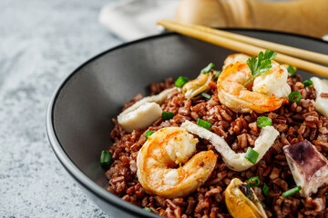 delicious red rice with shrimps and seafood on a gray stone background